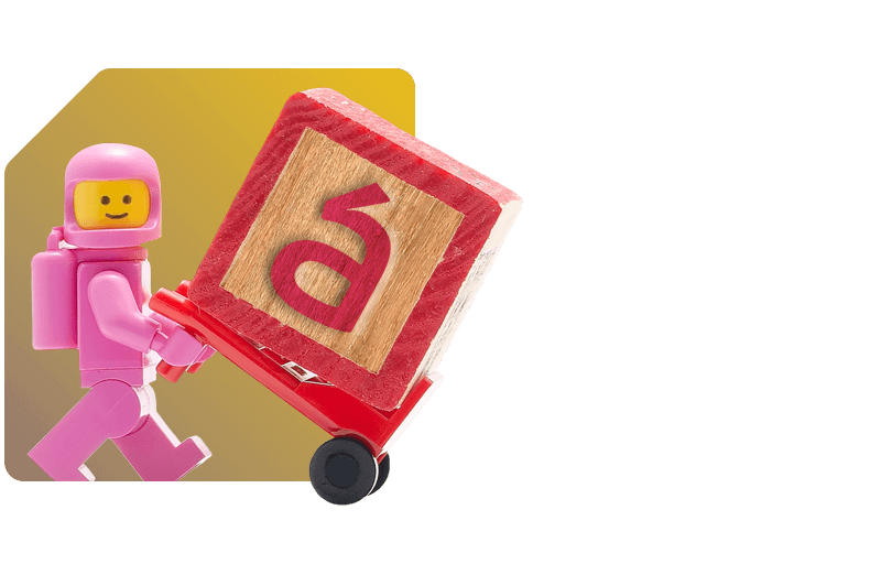 Personagem de brinquedo empurrando um bloco com a letra "á"